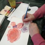 Close up of participant in pink sweater painting with pink and purple paints